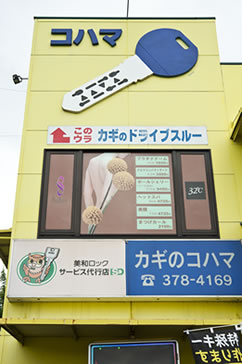 黄色い建物に大きな鍵の看板がある「カギのコハマ」。この2階がサロンです
